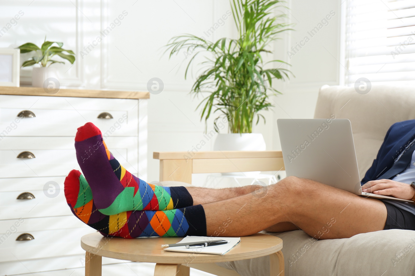 Photo of Businessman in jacket and underwear working on laptop at home, closeup