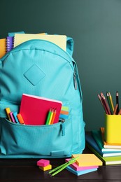 Photo of Backpack with different school stationery on white table near chalkboard