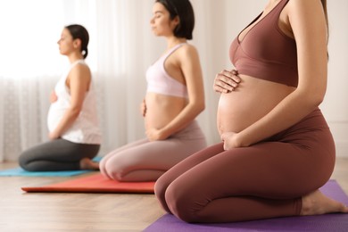 Photo of Group of pregnant women practicing yoga in gym, closeup