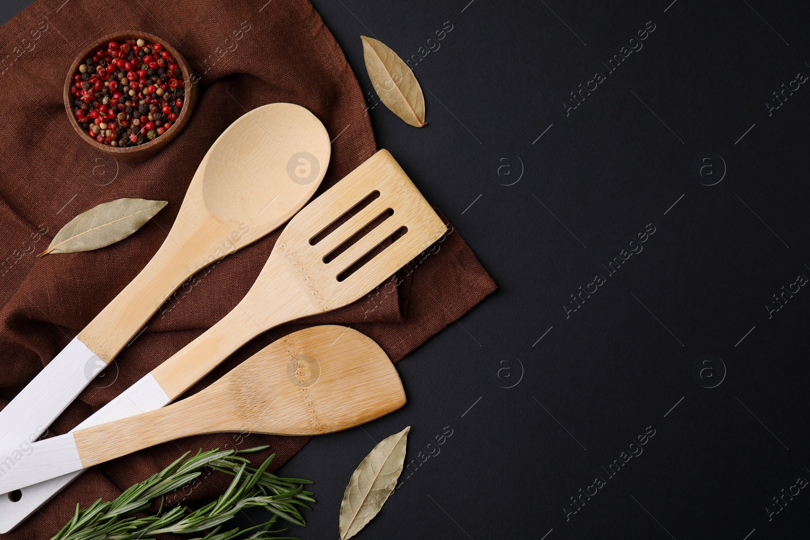 Photo of Set of wooden kitchen utensils and spices on black table, flat lay. Space for text