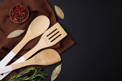 Photo of Set of wooden kitchen utensils and spices on black table, flat lay. Space for text