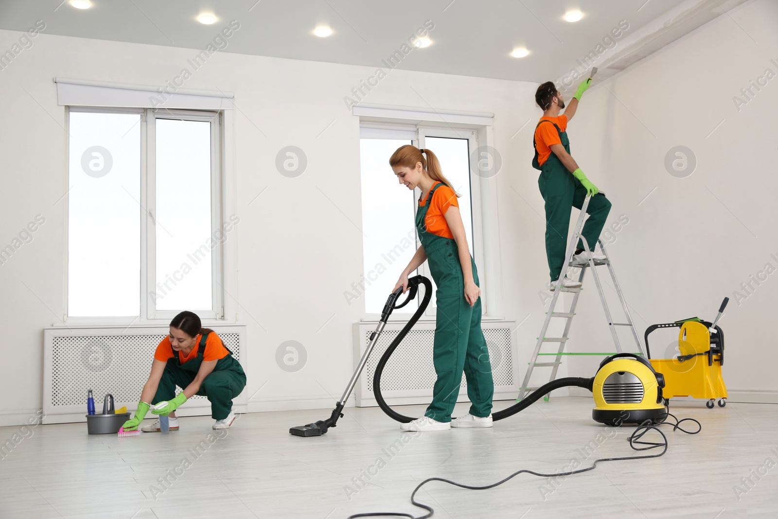 Photo of Team of professional janitors in uniforms cleaning room