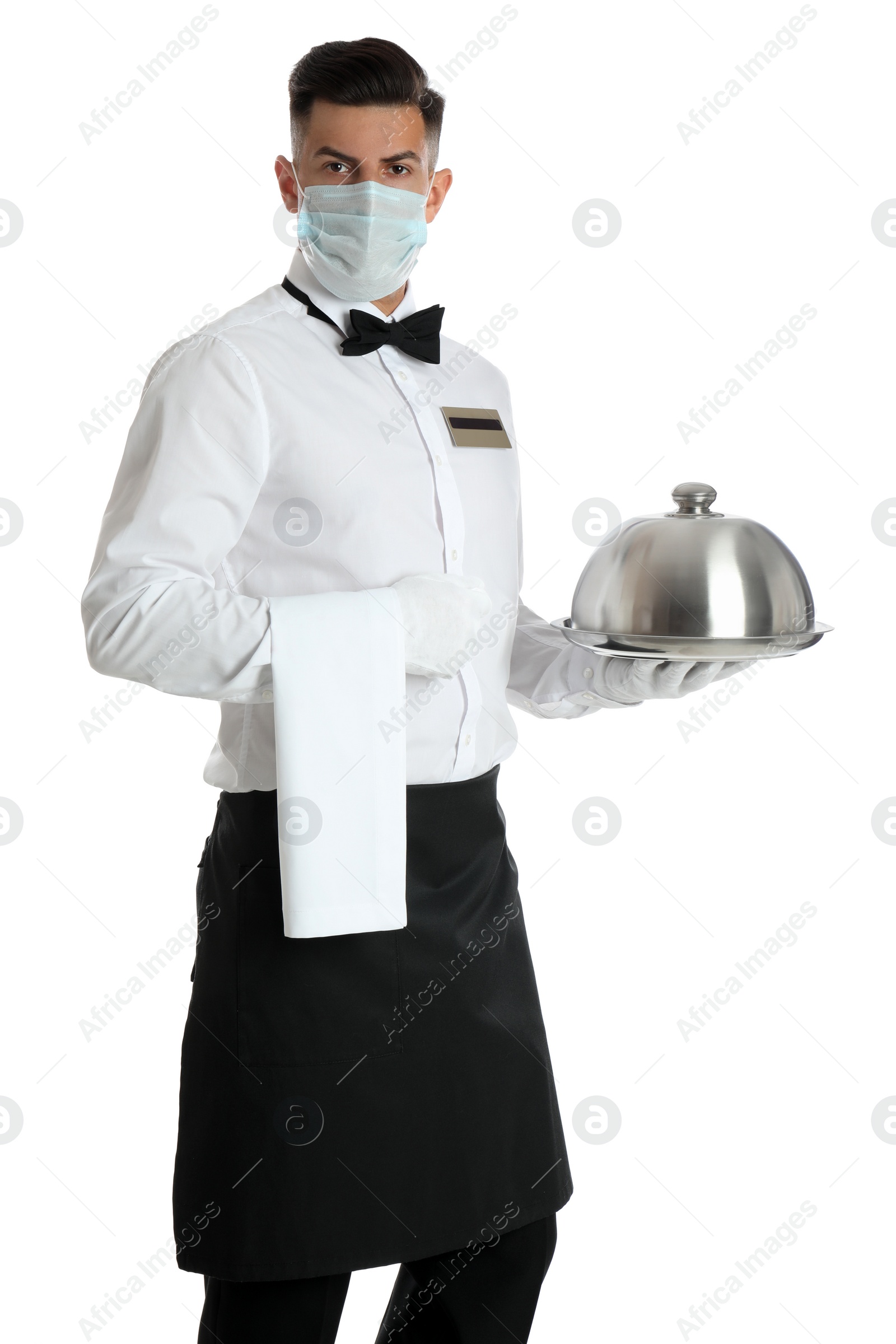 Photo of Waiter in medical face mask holding tray with lid on white background