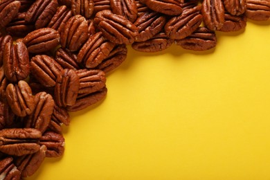 Heap of tasty nuts on yellow background, space for text
