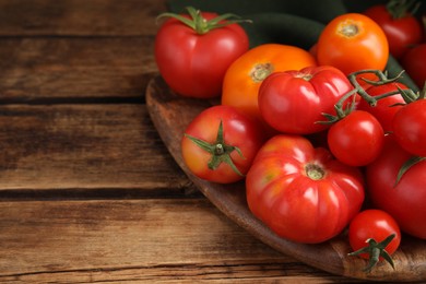 Many different ripe tomatoes on wooden table. Space for text