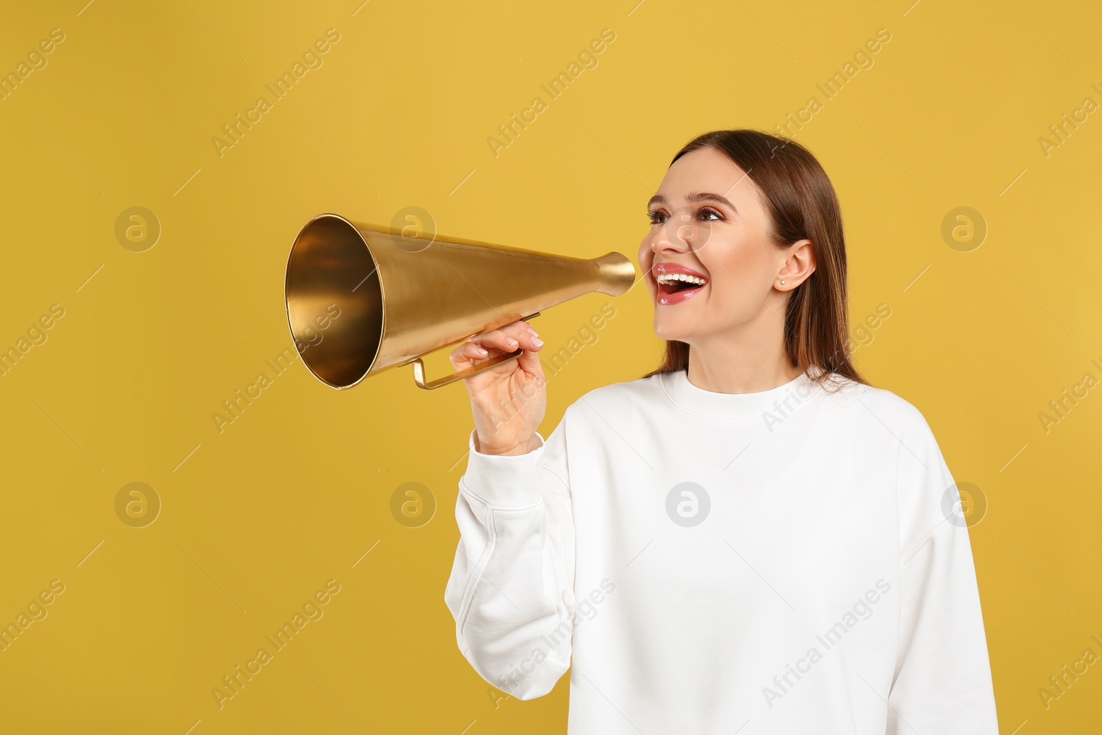 Photo of Young woman with vintage megaphone on yellow background