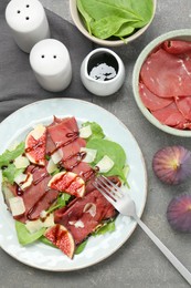 Photo of Flat lay composition with delicious bresaola salad on grey textured table