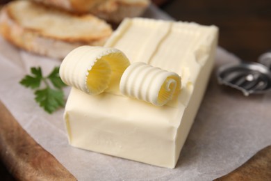 Photo of Tasty butter and spoon on wooden board, closeup