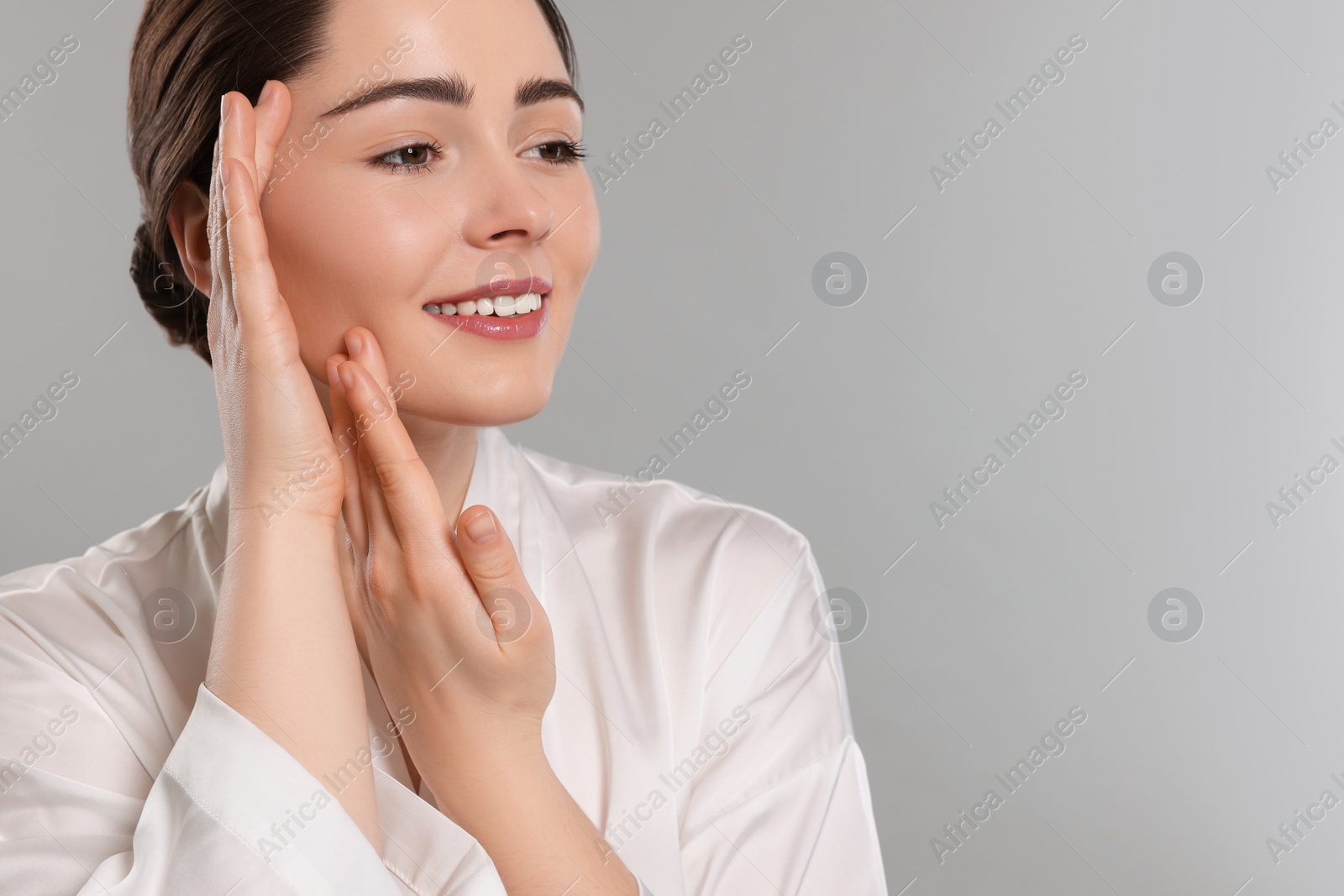 Photo of Young woman massaging her face on grey background. Space for text