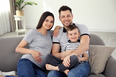 Father, son and pregnant mother spending time together on sofa at home. Family time