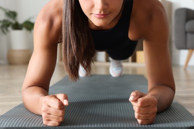 Photo of Young woman doing plank exercise at home, closeup