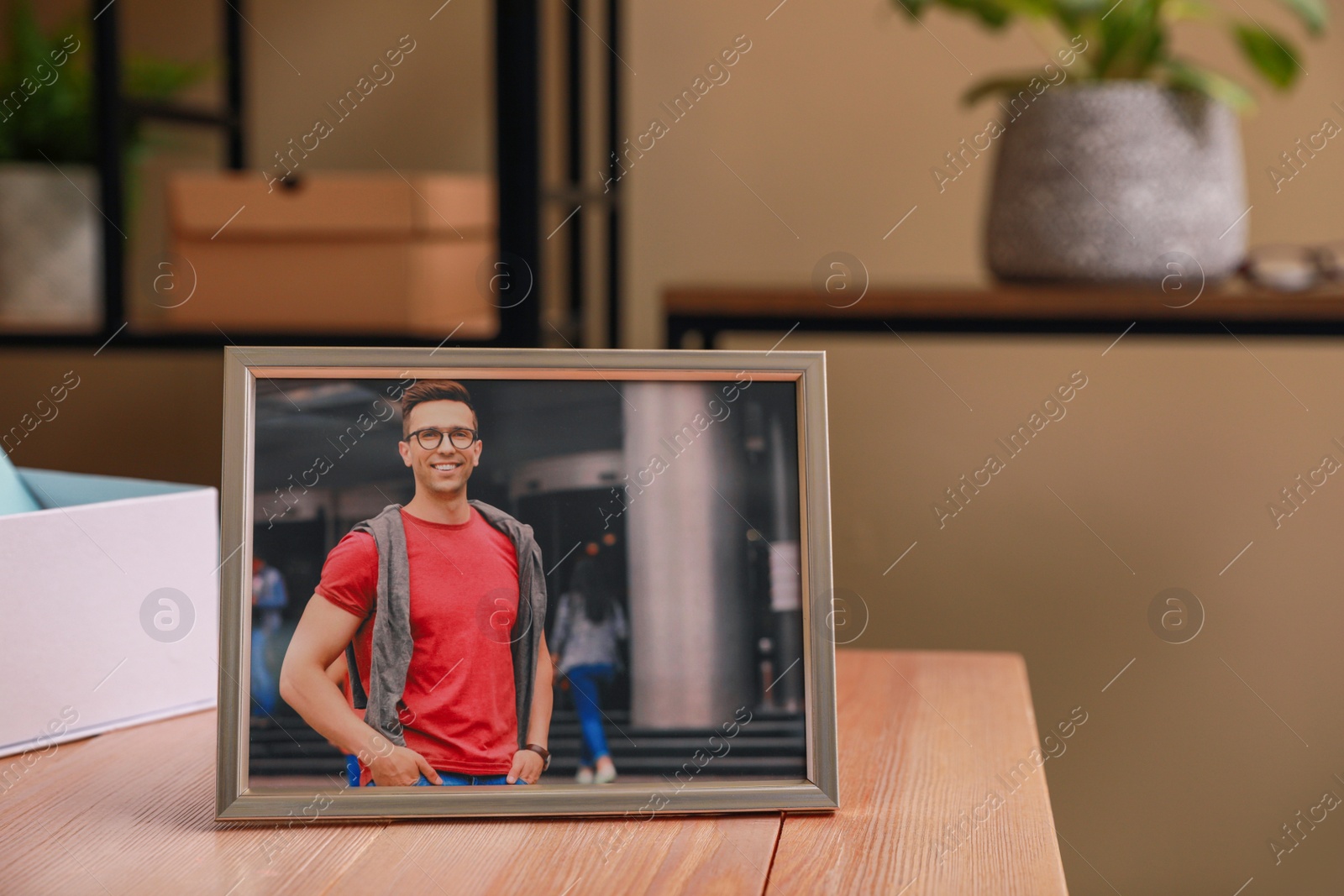 Photo of Framed photo of happy young man on wooden table in room. Space for text