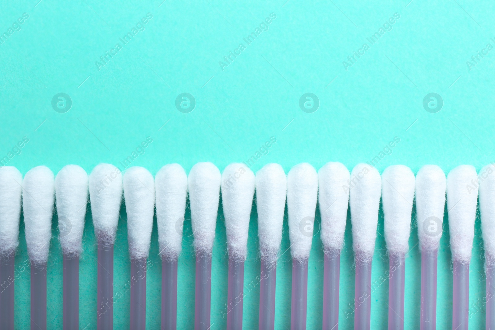 Photo of Many cotton buds on turquoise background, flat lay. Space for text