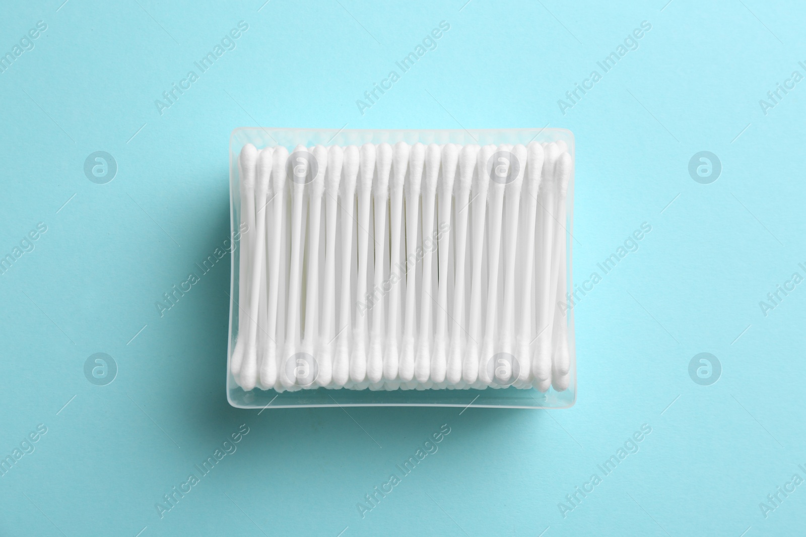 Photo of Plastic container with cotton swabs on color background, top view