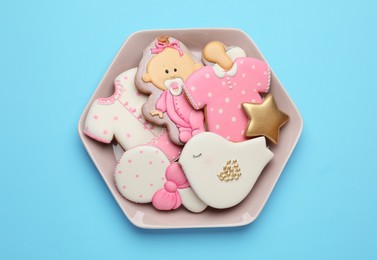 Photo of Plate of baby shower cookies on turquoise background, top view