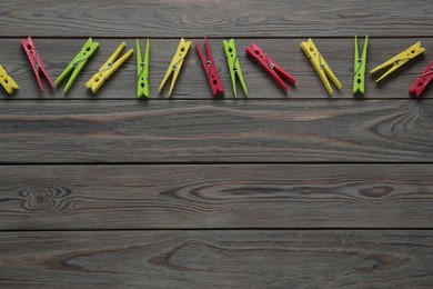 Photo of Colorful plastic clothespins on wooden background, flat lay. Space for text