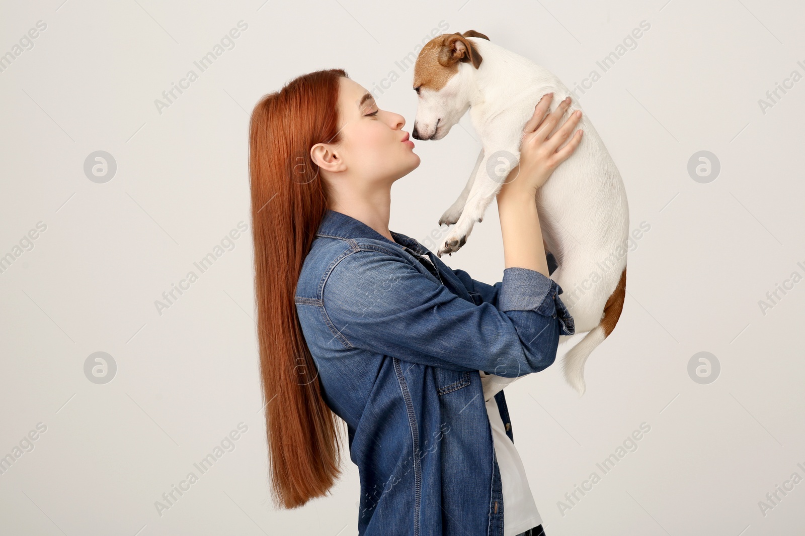 Photo of Woman kissing cute Jack Russell Terrier dog on white background. Space for text