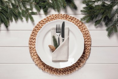 Photo of Beautiful festive place setting with cutlery and fir branches for Christmas dinner on white wooden table, flat lay