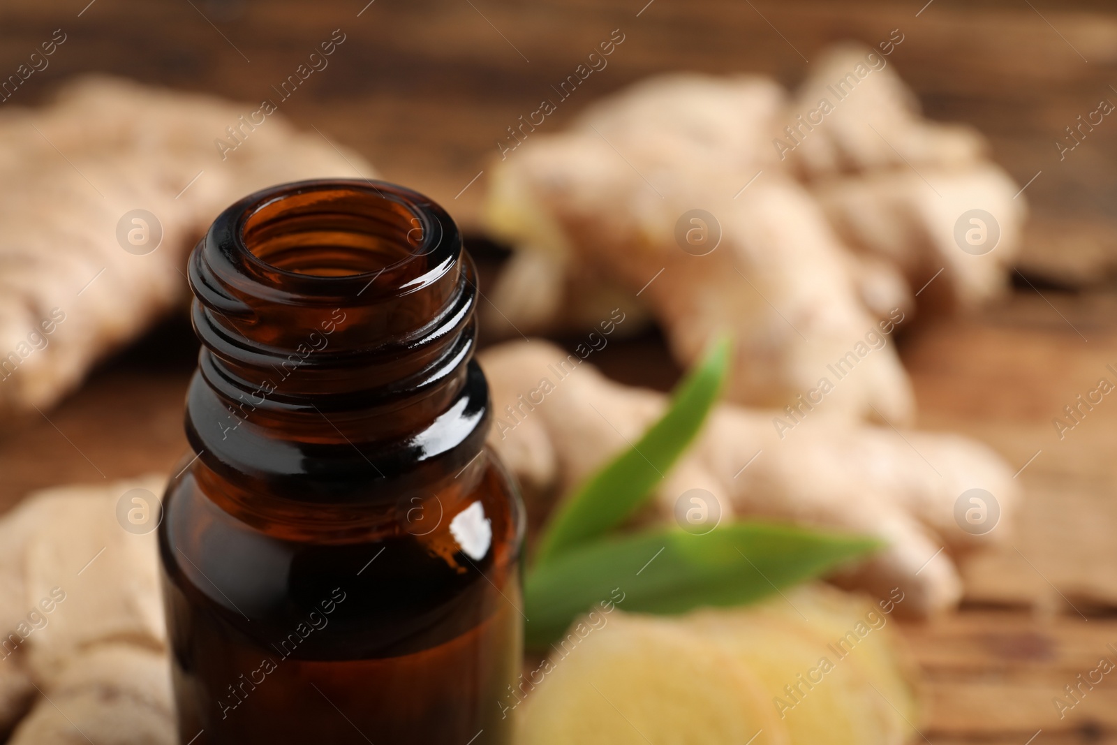 Photo of Glass bottle of ginger essential oil on table, closeup. Space for text