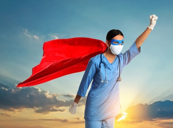 Image of Medical workers fighting with dangerous diseases. Doctor dressed as superhero posing against sky
