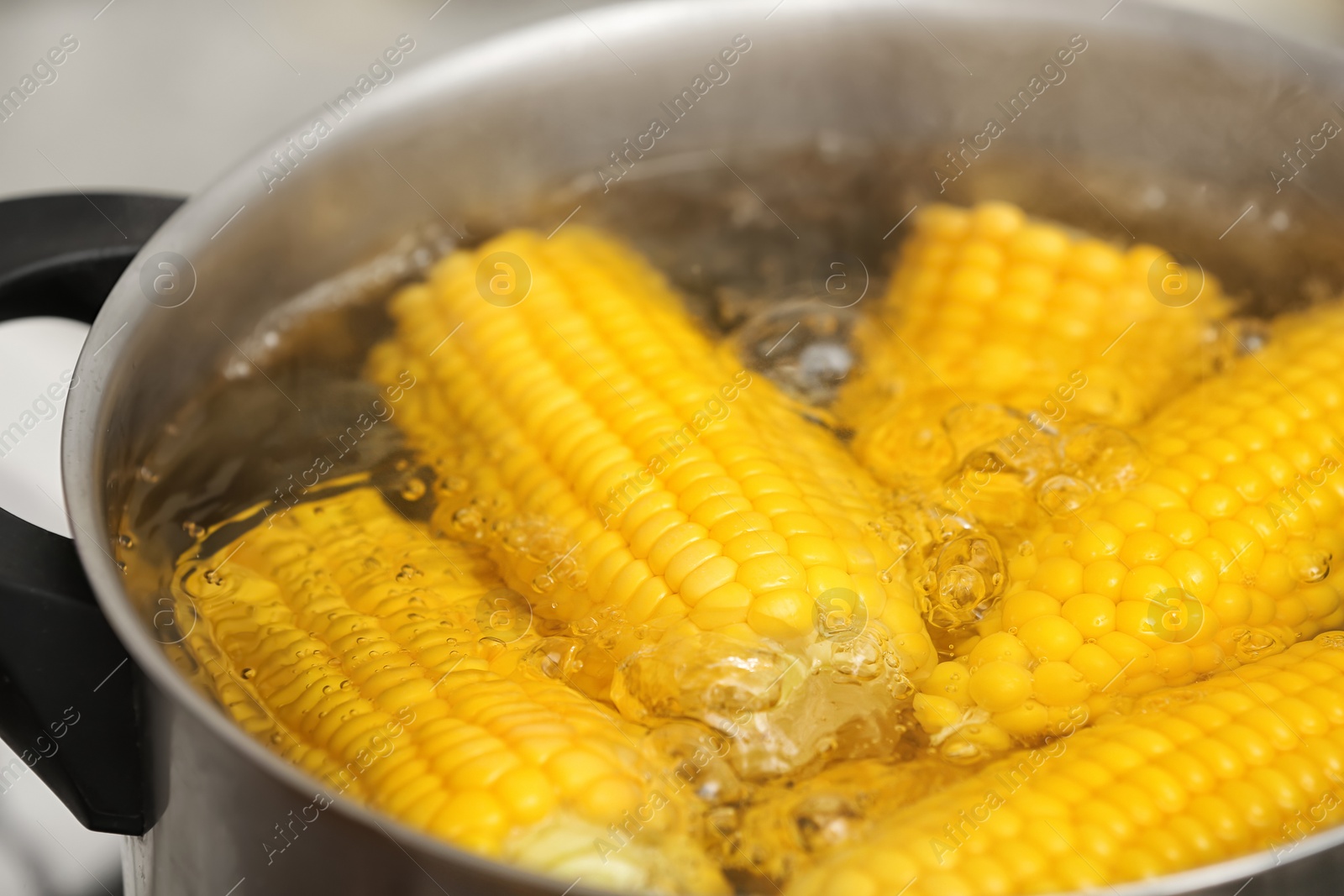 Photo of Stewpot with boiling water and corn cobs, closeup