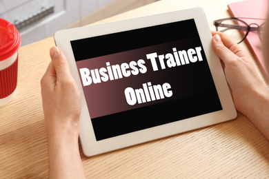 Woman working with tablet at table indoors, closeup. Business trainer online