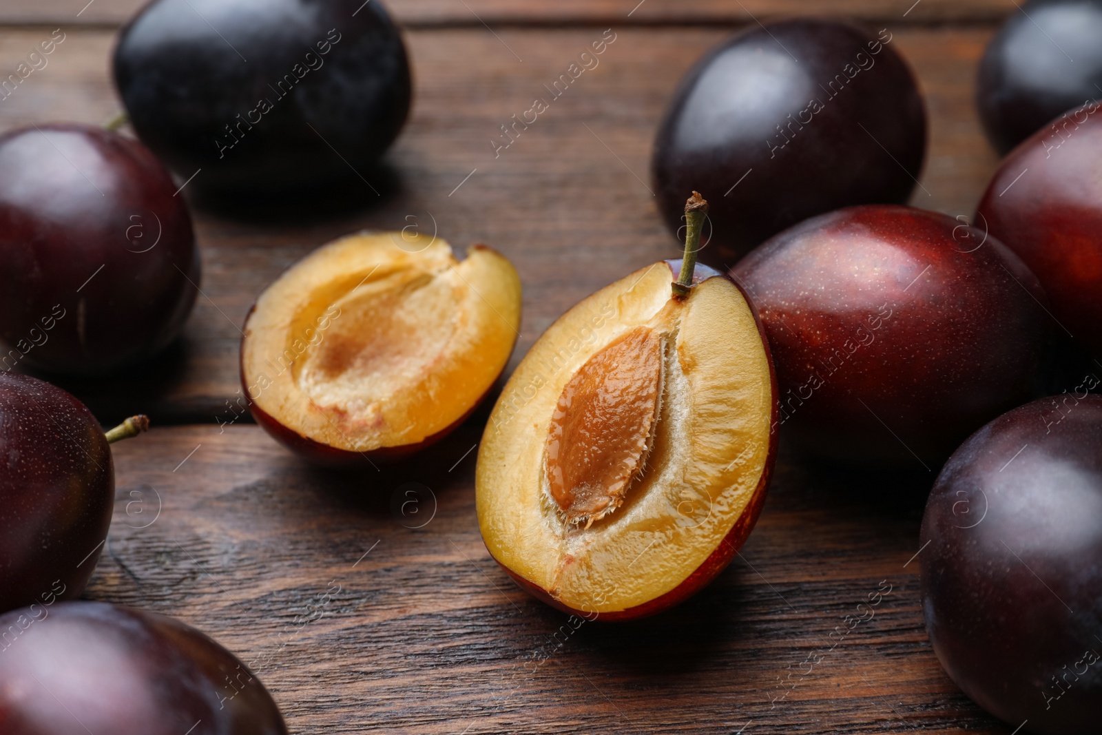 Photo of Tasty ripe plums on wooden table, closeup