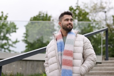 Photo of Smiling man in warm scarf outdoors, low angle view. Space for text