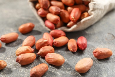 Photo of Fresh unpeeled peanuts on grey table, closeup