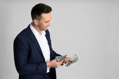 Photo of Man counting money on light grey background. Space for text