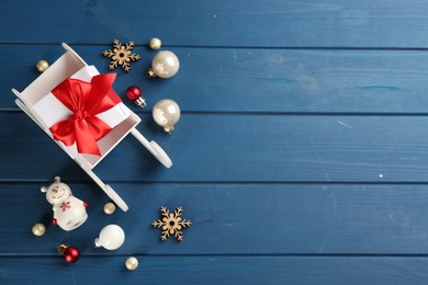 Photo of Beautiful Christmas composition with miniature sleigh on blue wooden table, flat lay. Space for text