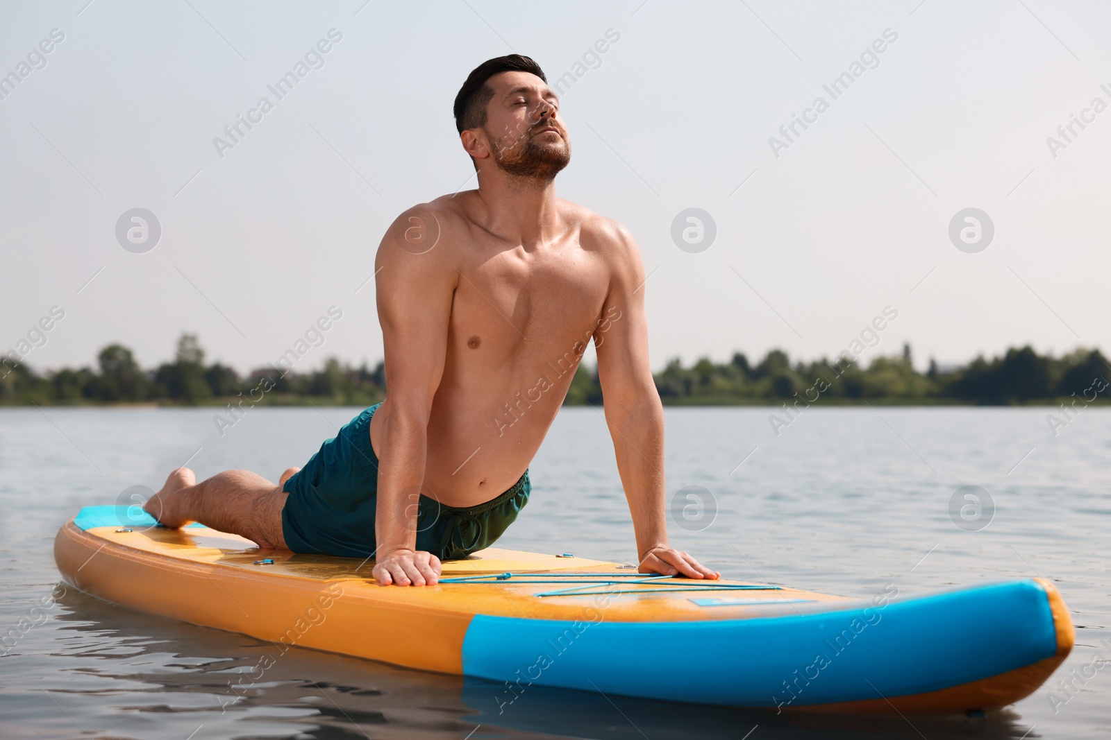 Photo of Man practicing yoga on SUP board on river