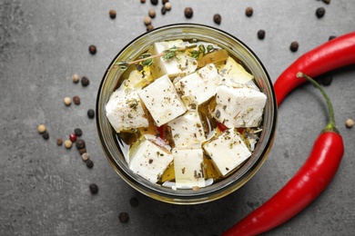 Photo of Jar with feta cheese marinated in oil on grey table, flat lay. Pickled food