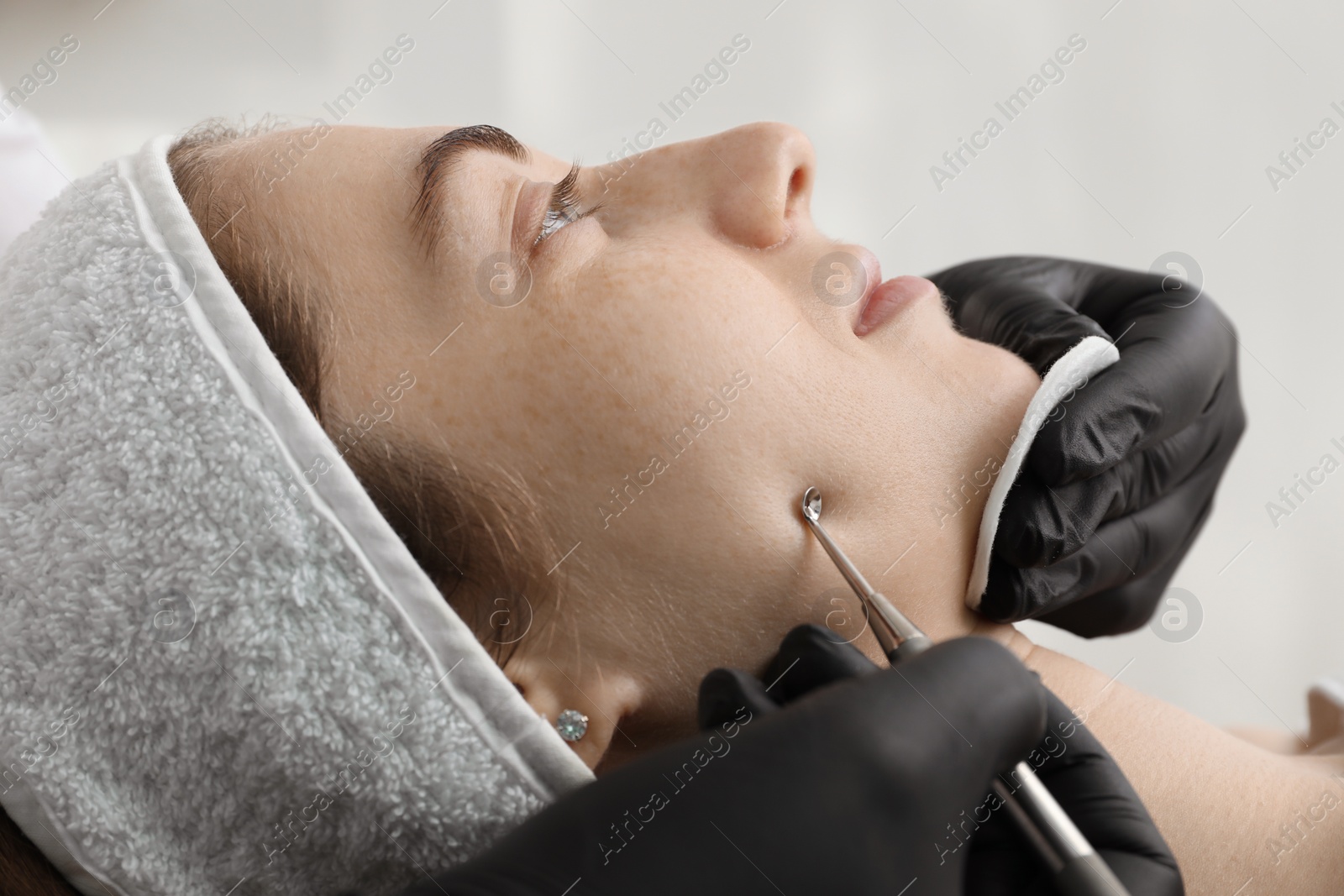 Photo of Cosmetologist using scrubber, closeup. Client having cleansing procedure