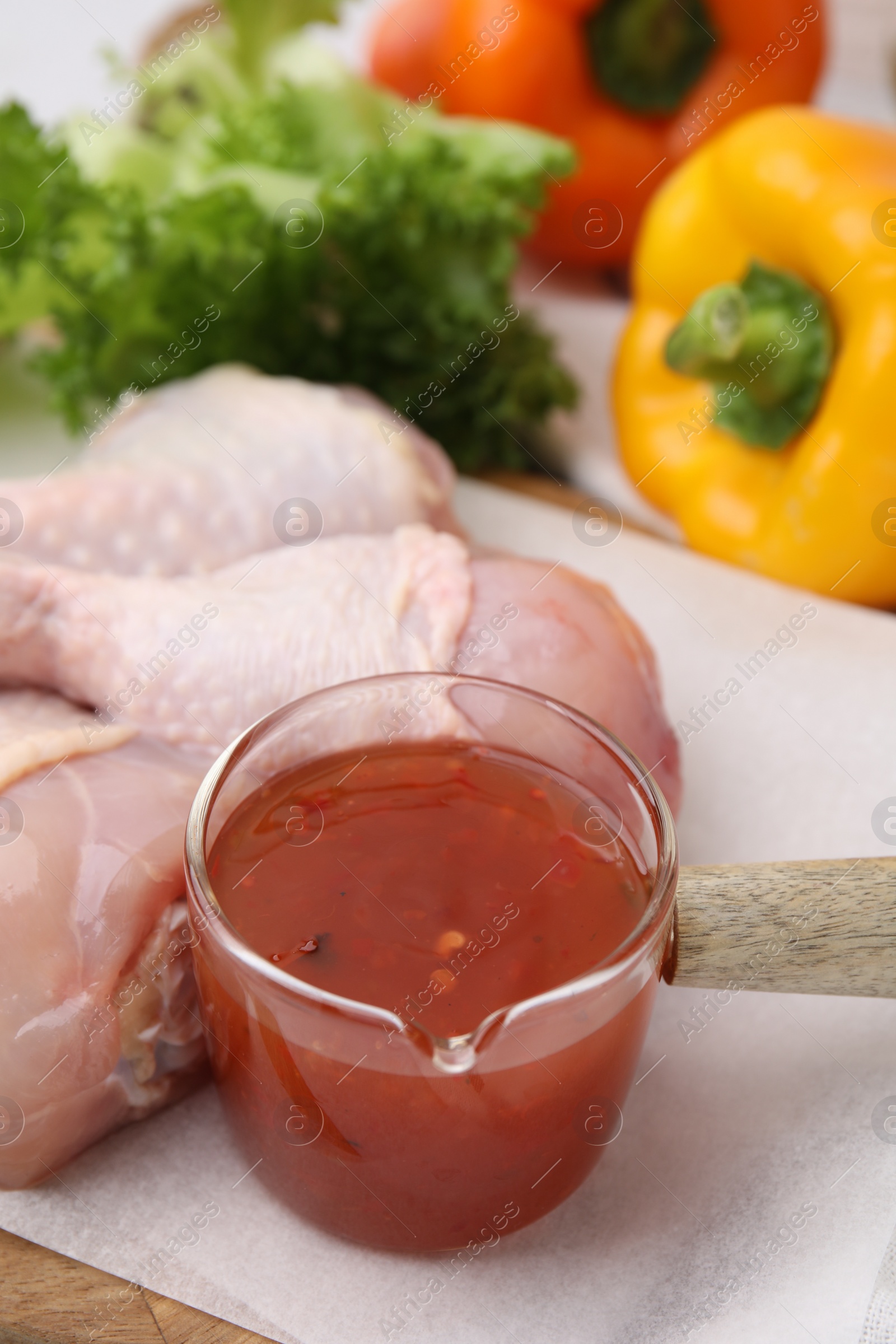 Photo of Fresh marinade and raw chicken drumsticks on board, closeup