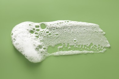 Photo of Smudge of white washing foam on olive background, top view