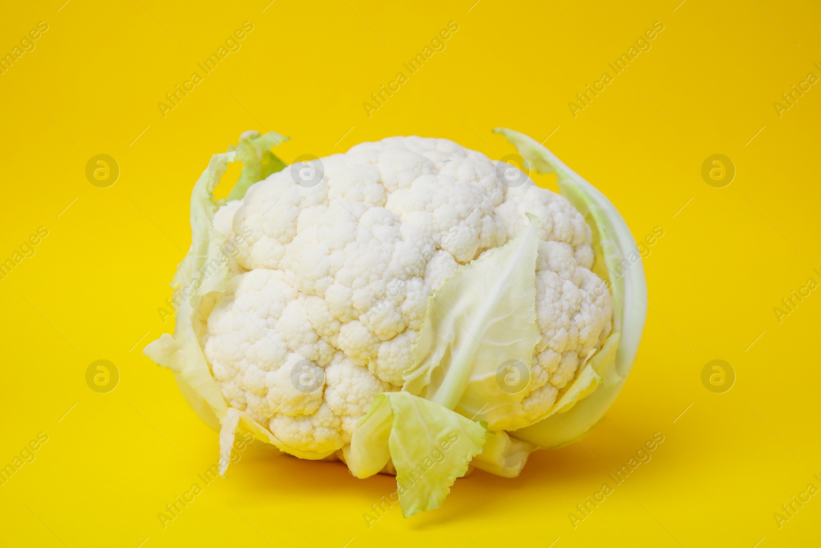 Photo of Whole fresh raw cauliflower on yellow background