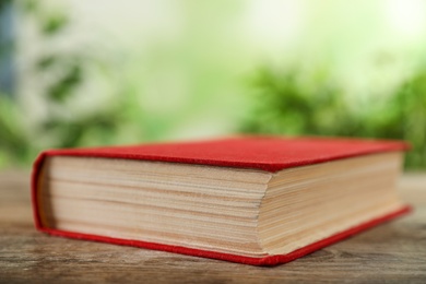 Photo of Closed hardcover book on wooden table against blurred background
