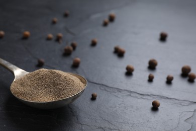 Ground black pepper and corns on black table, closeup