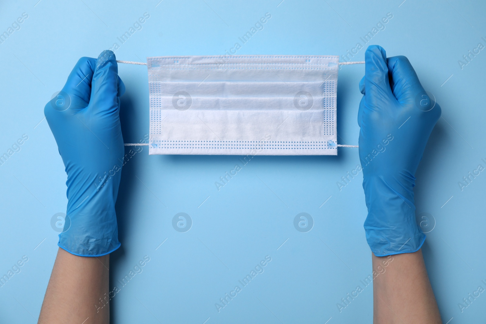 Photo of Woman with protective mask on light blue background, top view. Safety equipment