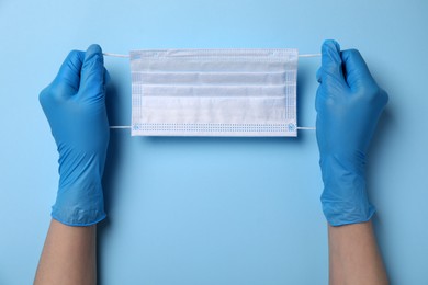 Woman with protective mask on light blue background, top view. Safety equipment