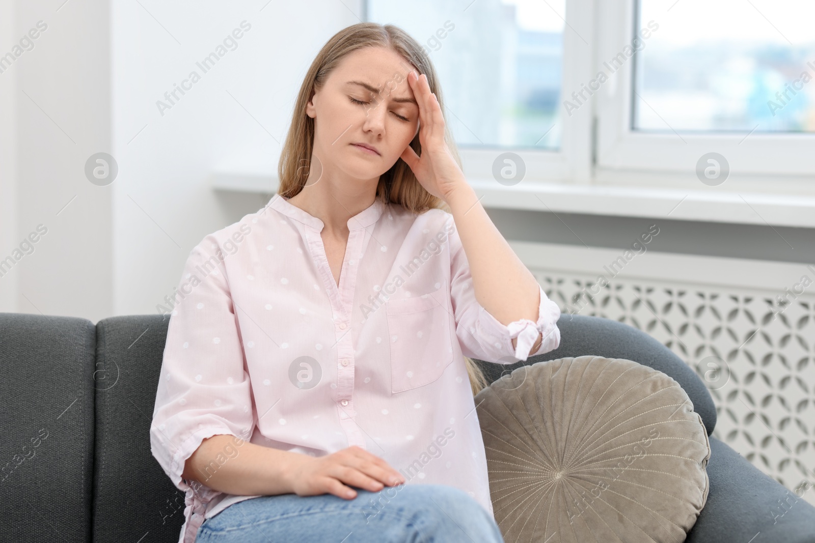 Photo of Overwhelmed young woman suffering from headache at home