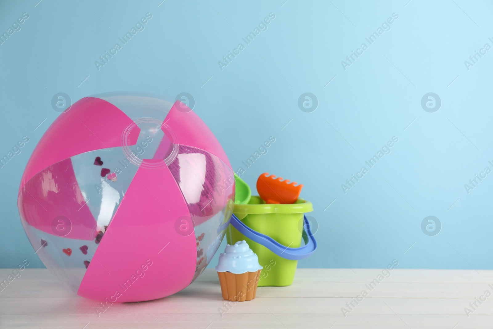 Photo of Beach ball and sand toys on white wooden table. Space for text