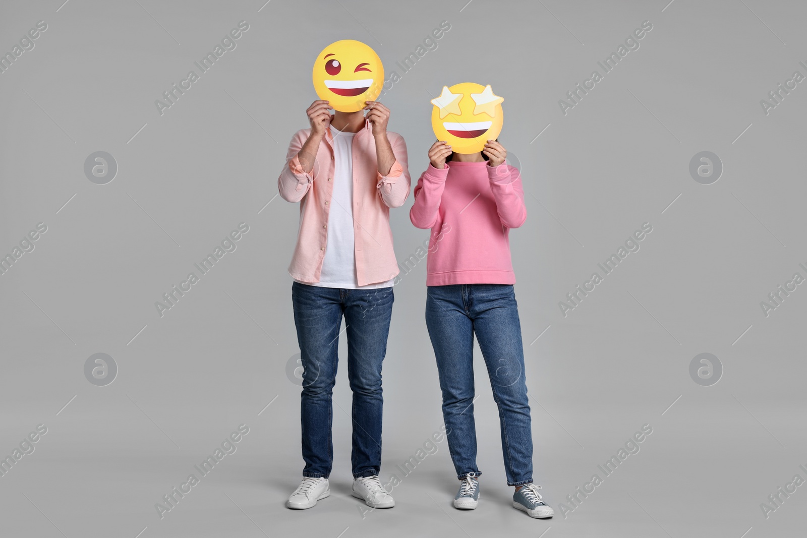 Photo of People covering faces with happy emoticons on grey background