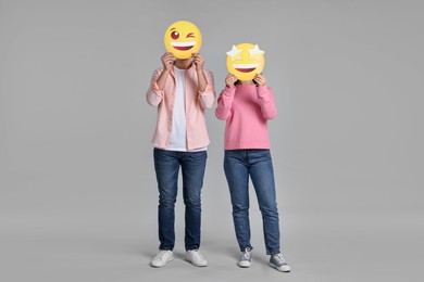 Photo of People covering faces with happy emoticons on grey background