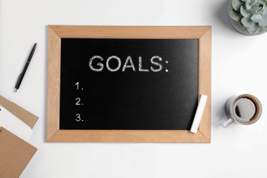 Image of Blackboard with word GOALS and empty checklist on white background, flat lay