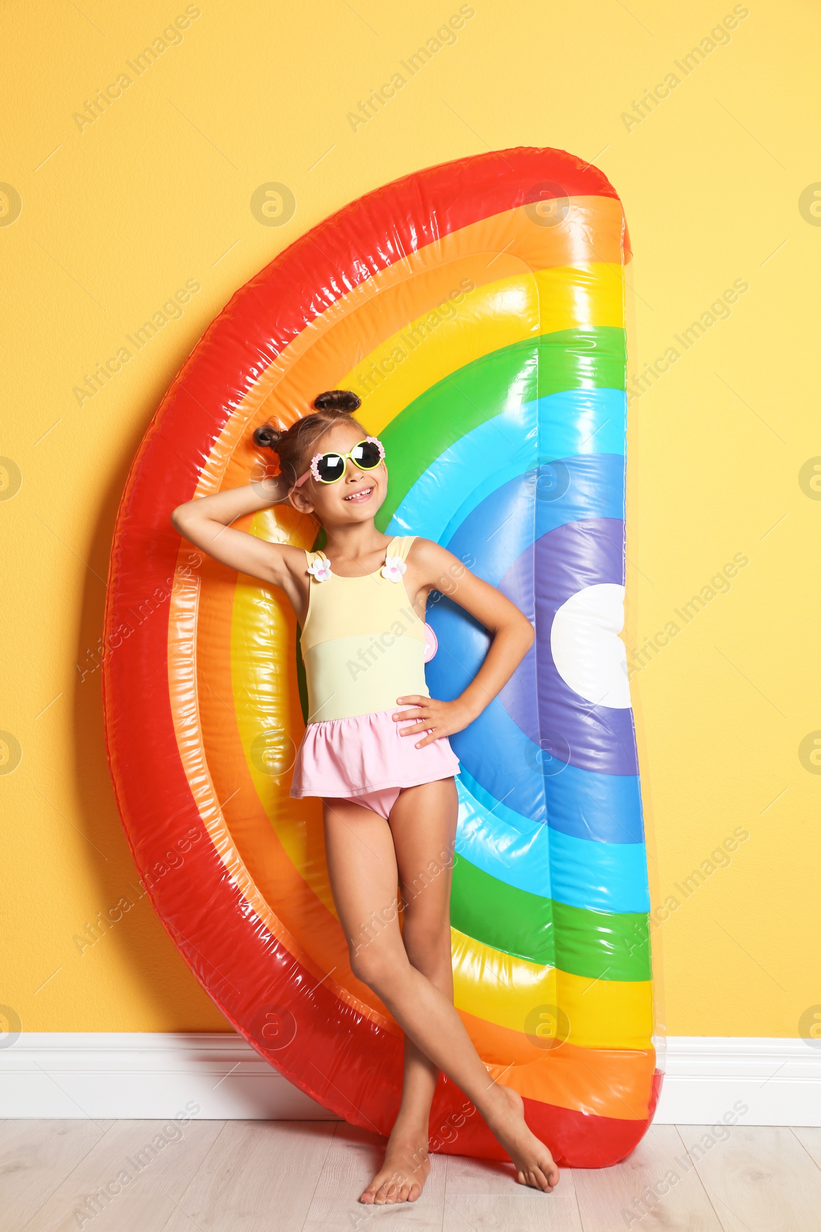 Photo of Cute little girl with inflatable mattress near color wall