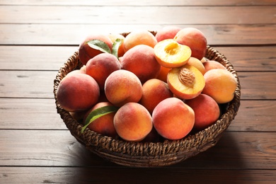 Photo of Wicker basket with fresh sweet peaches on wooden table