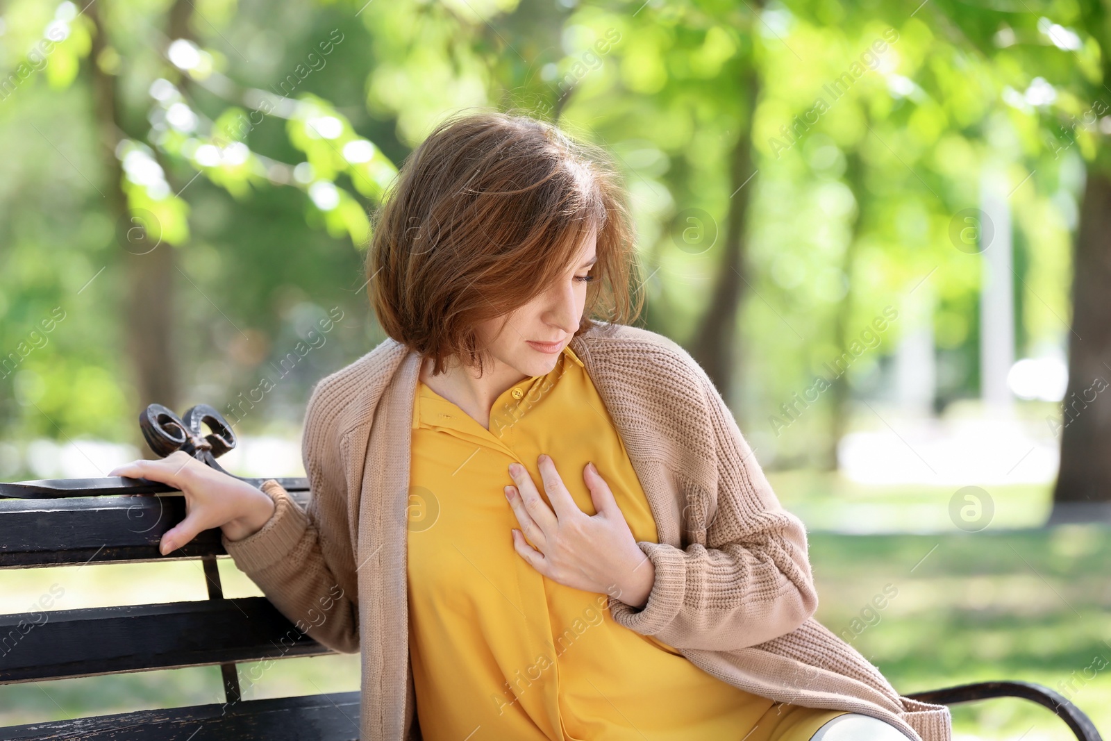 Photo of Mature woman having heart attack on bench in park