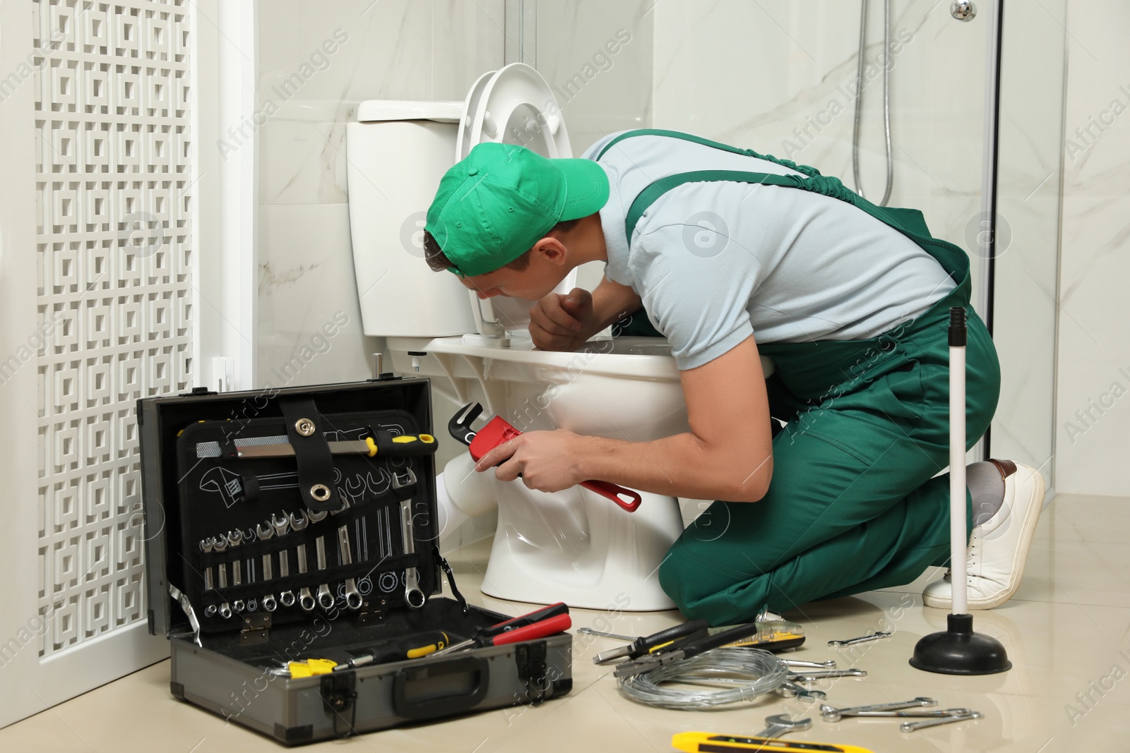 Photo of Professional plumber repairing toilet bowl in bathroom